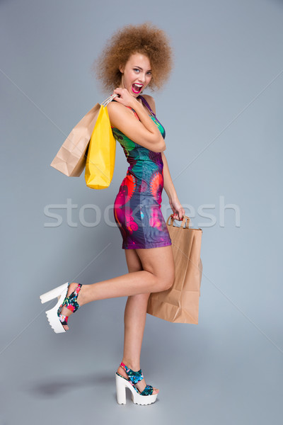 Full length portrait of happy curly woman with shopping bags  Stock photo © deandrobot