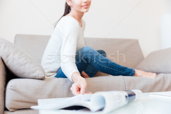 Stock photo: Woman stretching hand to take magazine at home