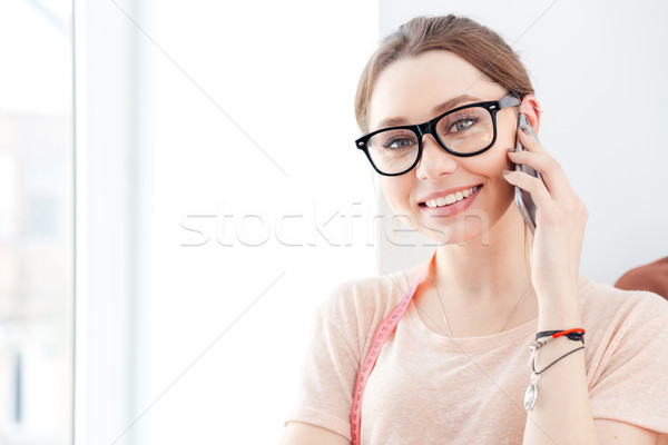 Woman seamstress talking on mobile phone in studio Stock photo © deandrobot