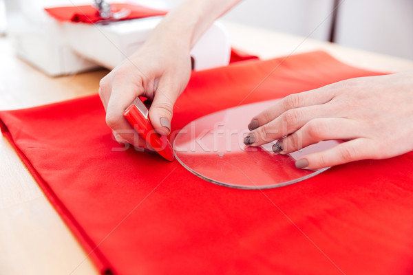 Hands of woman seamstress working with pattern and red textile Stock photo © deandrobot