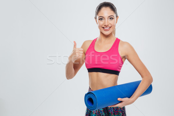 Fitness woman holding yoga mat and showing thumb up Stock photo © deandrobot