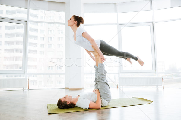 Beautiful young couple doing acro yoga in studio together Stock photo © deandrobot