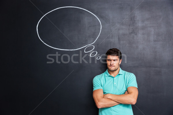 Sad frowning young man standing over chalkboard background Stock photo © deandrobot