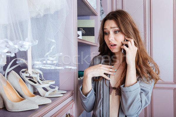 Beautiful young girl using mobile phone in a wardrobe Stock photo © deandrobot