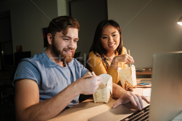 Cheerful business colleagues working at night in office while eating Stock photo © deandrobot