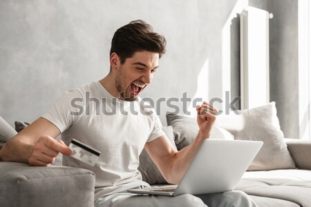 Happy man working on laptop and drinking a coffee Stock photo © deandrobot