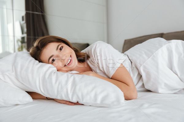 Woman dressed in white t-shirt lies in bed Stock photo © deandrobot