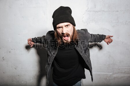 Stock photo: Vertical image of Hipster in snap back showing gun gestures