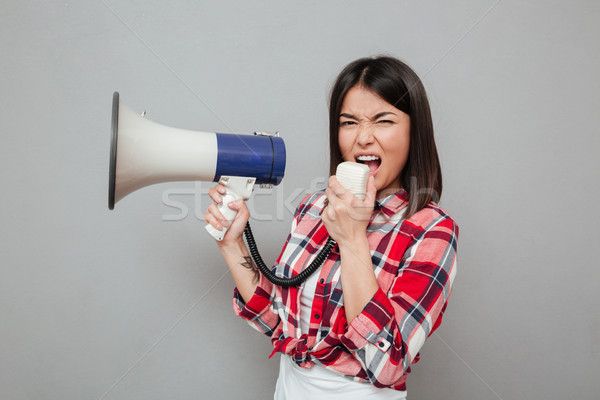 Screaming young asian woman holding loudspeaker. Stock photo © deandrobot