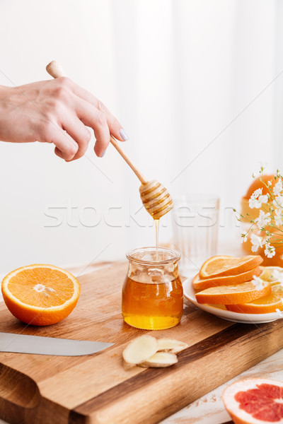 Woman standing near table with citruses and holding honey. Stock photo © deandrobot
