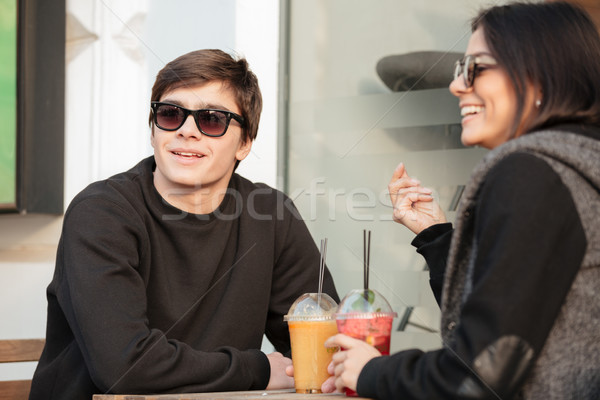 Cheerful young lady sitting outdoors with her brother drinking juice Stock photo © deandrobot
