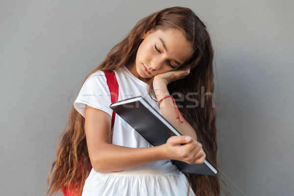 Tired brunette schoolgirl with long hair sleeping on book Stock photo © deandrobot