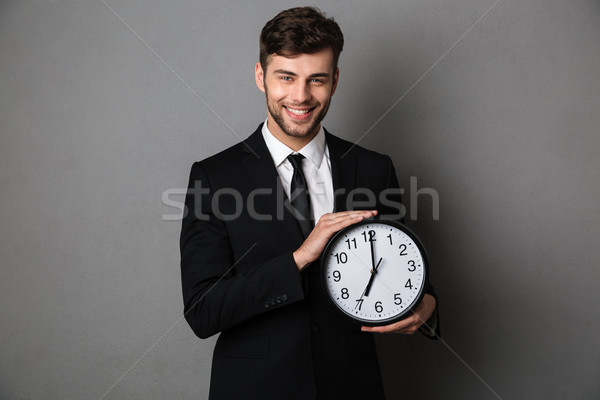 Stock photo: Close-up photo of smiling handsome man in black suit holding clo