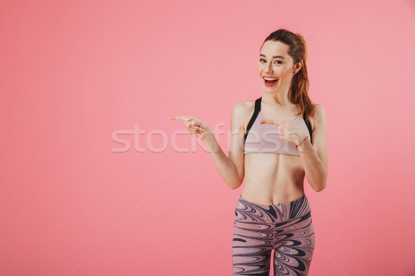 Happy sportswoman pointing on copyspace while looking at the camera Stock photo © deandrobot