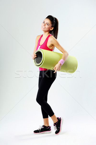 Young sport woman with yoga mat on gray background Stock photo © deandrobot