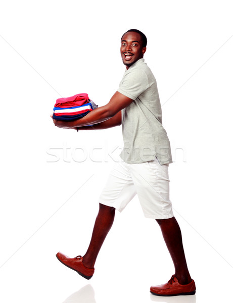 Studio shot of a happy african man holding his clothes over white background Stock photo © deandrobot