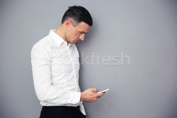 Businessman using smartphone over gray background Stock photo © deandrobot