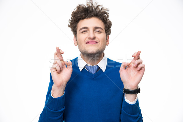Young man with crossed fingers over white background Stock photo © deandrobot