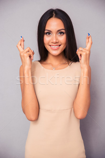 Smiling woman standing with crossed fingers  Stock photo © deandrobot