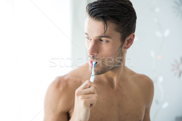 Handsome man brushing teeth Stock photo © deandrobot