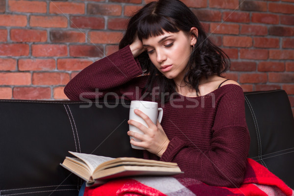 Stock photo: Attrative pensive young woman reading book and drinking tea 