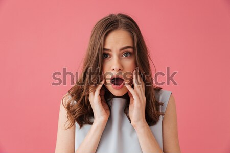 Stock photo: Wondered happy young woman standing and talking on mobile phone 