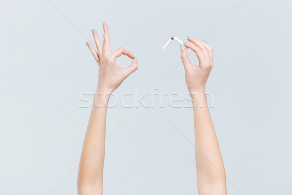 Stock photo: Female hands holding broken cigarette and showing ok sign