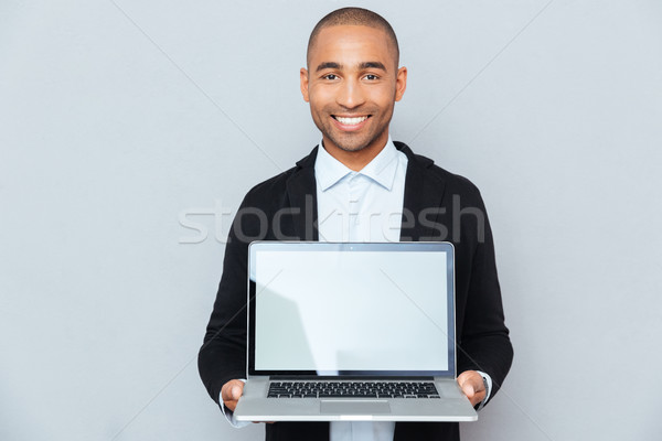 Uśmiechnięty młody człowiek ekranu laptop Zdjęcia stock © deandrobot