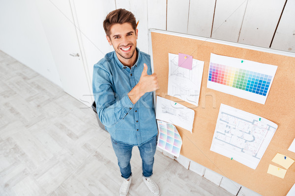 Man standing at task board and showing thumbs up gesture Stock photo © deandrobot
