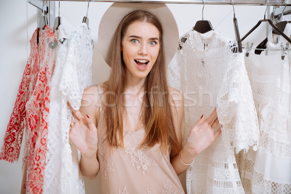 Cheerful excited young woman choosing dress in clothing store Stock photo © deandrobot