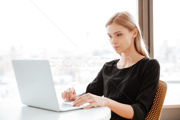 Concentrado mulher jovem trabalhador usando laptop quadro sessão Foto stock © deandrobot