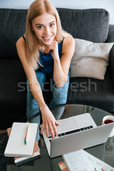 Cheerful charming young woman using laptop at home Stock photo © deandrobot