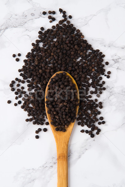 Top view of aa wooden spoon full of black peppercorns Stock photo © deandrobot