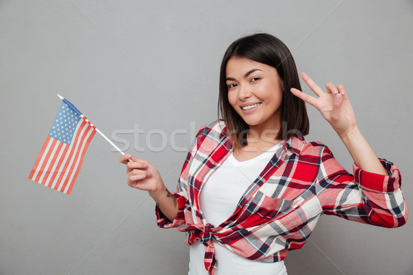 Cheerful woman holding USA flag over grey wall Stock photo © deandrobot