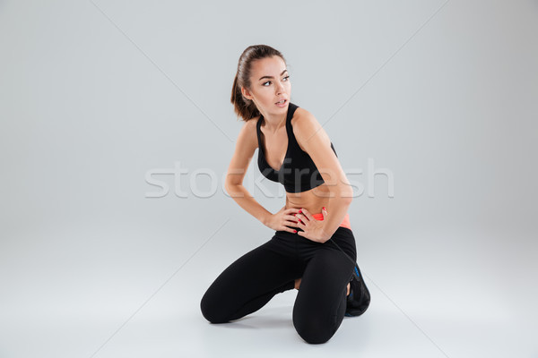 Cansado mujer de la aptitud sesión piso manos cadera Foto stock © deandrobot