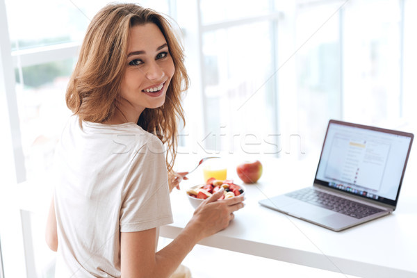 Stok fotoğraf: Arkadan · görünüm · genç · kadın · kahvaltı · dizüstü · bilgisayar · bakıyor · kamera