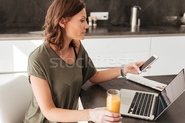 Side vew of casual woman using smartphone, computer and juice Stock photo © deandrobot