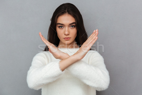 Portrait of a serious young woman showing crossed hands gesture Stock photo © deandrobot