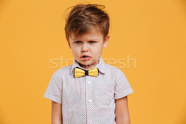 Sad little boy child standing isolated over yellow Stock photo © deandrobot