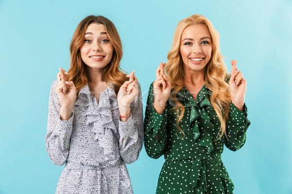 Two happy worried women in dresses praying with crossed fingers Stock photo © deandrobot