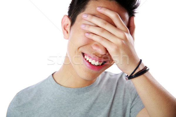 Portrait of a young man covering his eyes with his hand over white background Stock photo © deandrobot