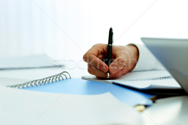 Closeup image of mans hand writing in notebook Stock photo © deandrobot