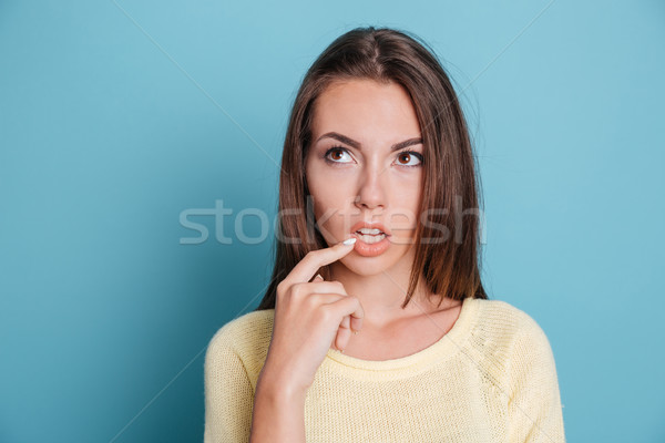 Close-up portrait of thoughtful girl thinking over blue background Stock photo © deandrobot