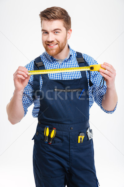 Portrait of young worker in uniform with yellow measuring tape Stock photo © deandrobot