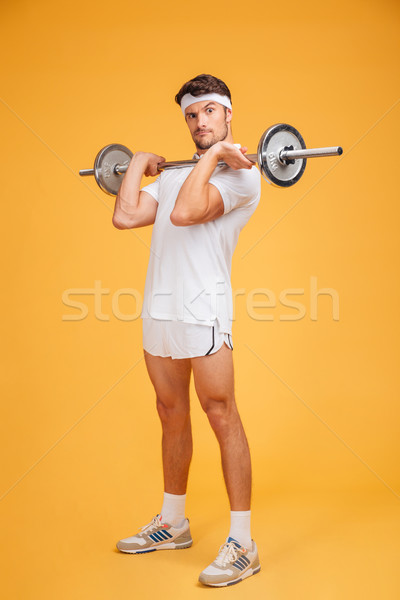 Playful young sportsman holding barbell and making funny face Stock photo © deandrobot