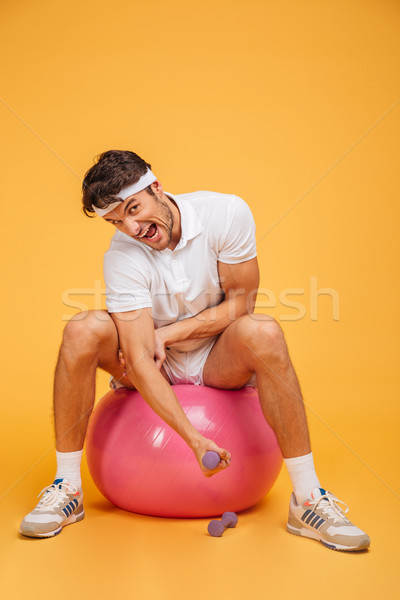 Sportsman man on fitness ball doing exercises with small dumbbells Stock photo © deandrobot