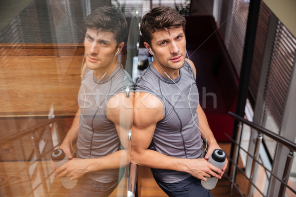 Sports man holding bottle with water and resting in gym Stock photo © deandrobot