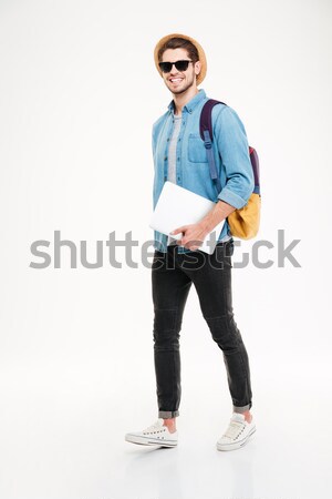 Cheerful young man with backpack walking and holding laptop Stock photo © deandrobot