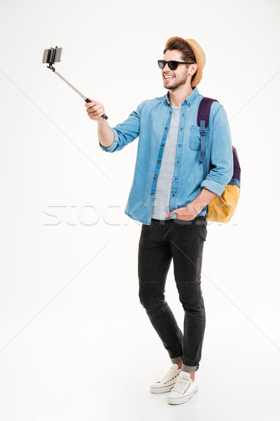 Smiling young man taking photos with smartphone and selfie stick Stock photo © deandrobot