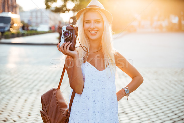 Young smiling blonde girl holding retro camera on the street Stock photo © deandrobot